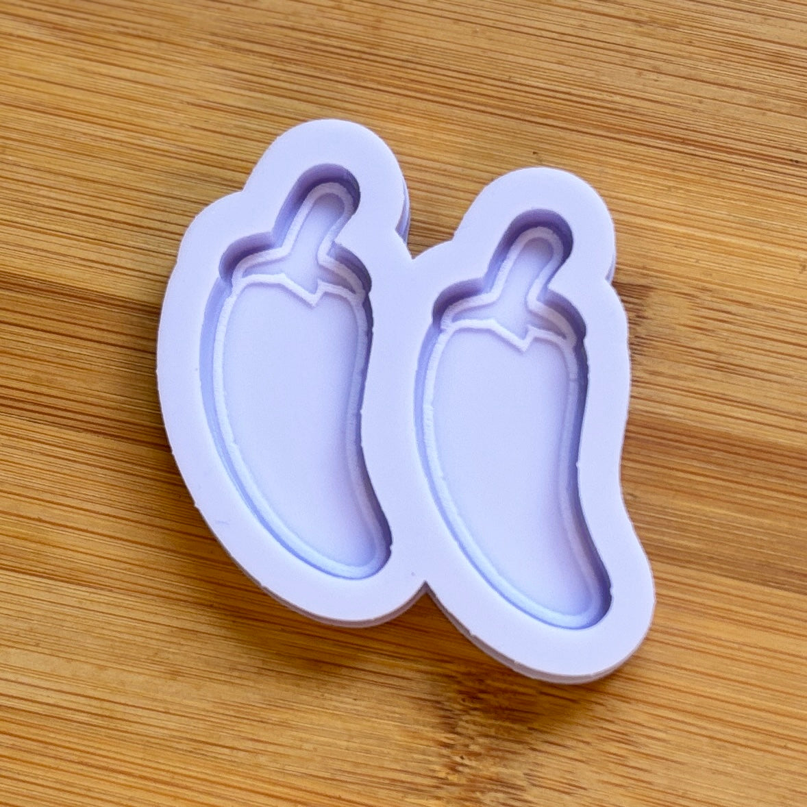 Silicone mold shaped like a chili pepper on a wooden surface