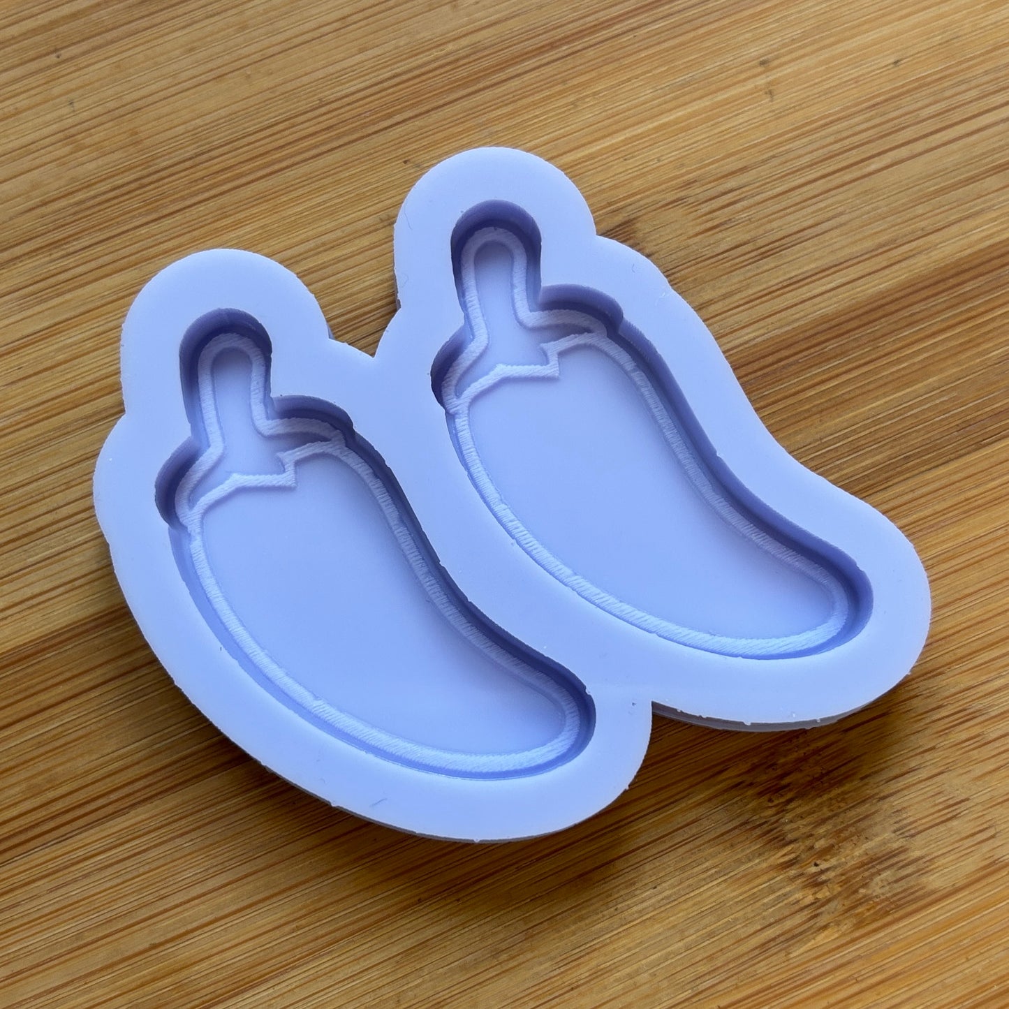 Silicone mold shaped like a chili pepper on a wooden surface