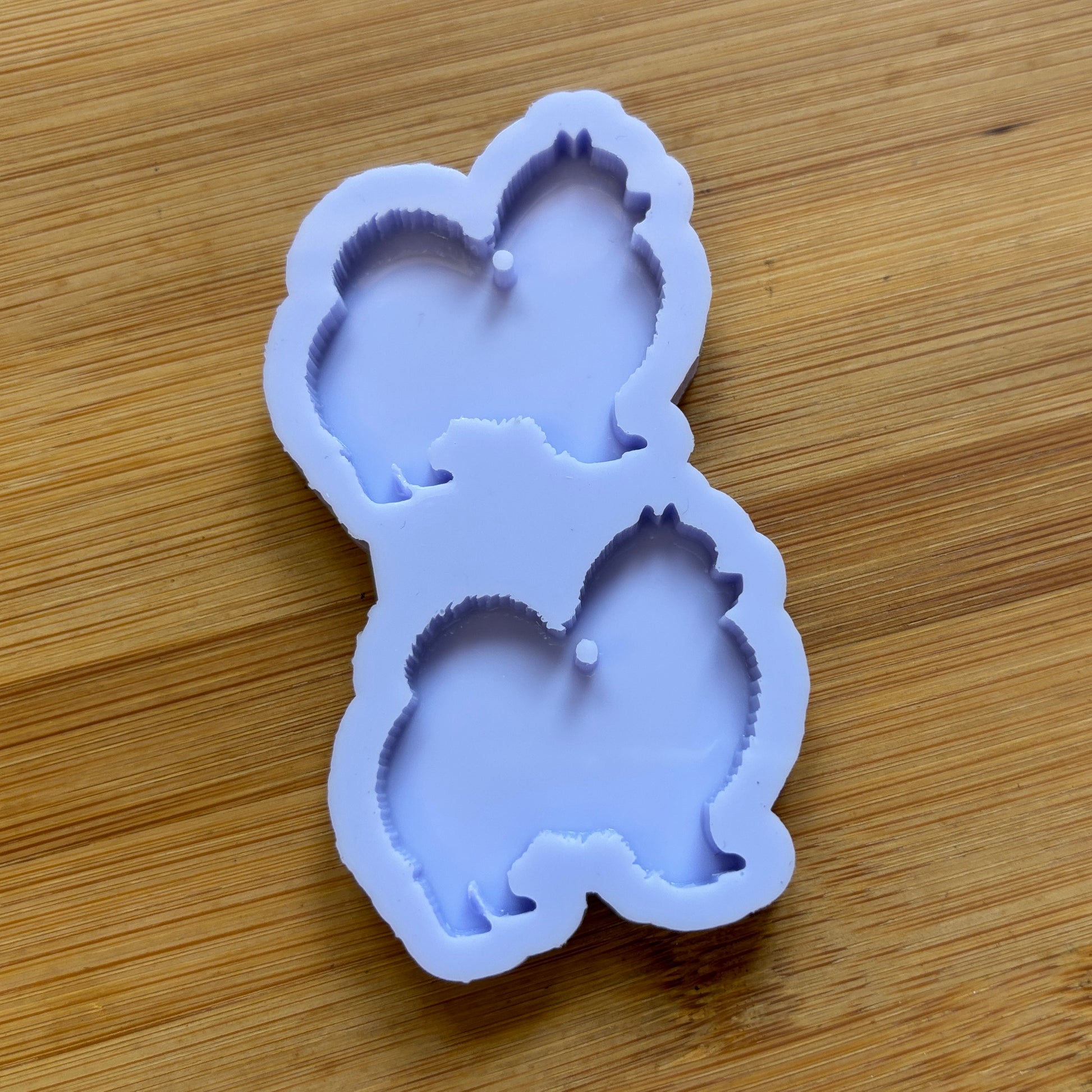 Silicone mold shaped like a Pomeranian dog on a wooden surface