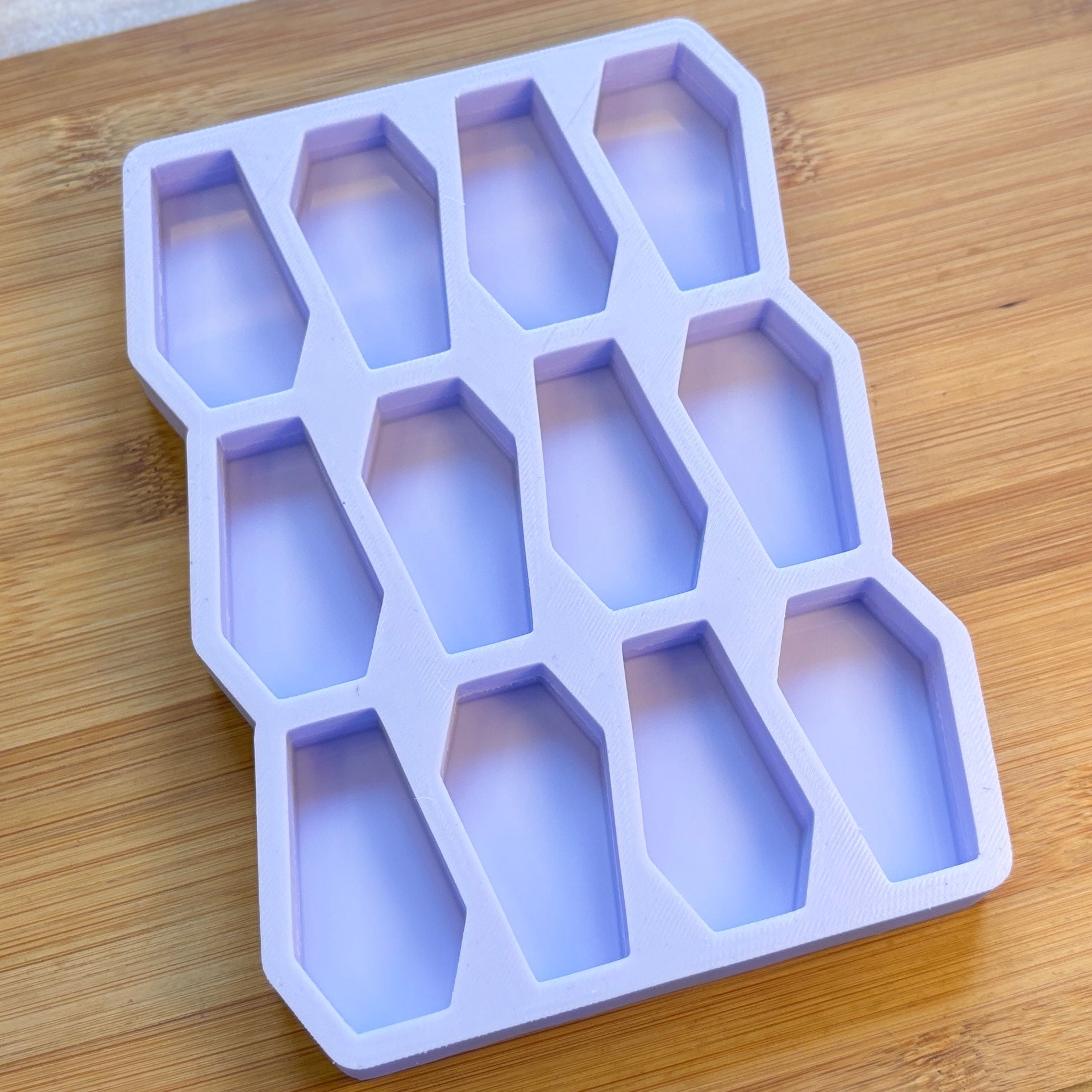 Silicone ice cube tray with coffin shapes on a wooden surface