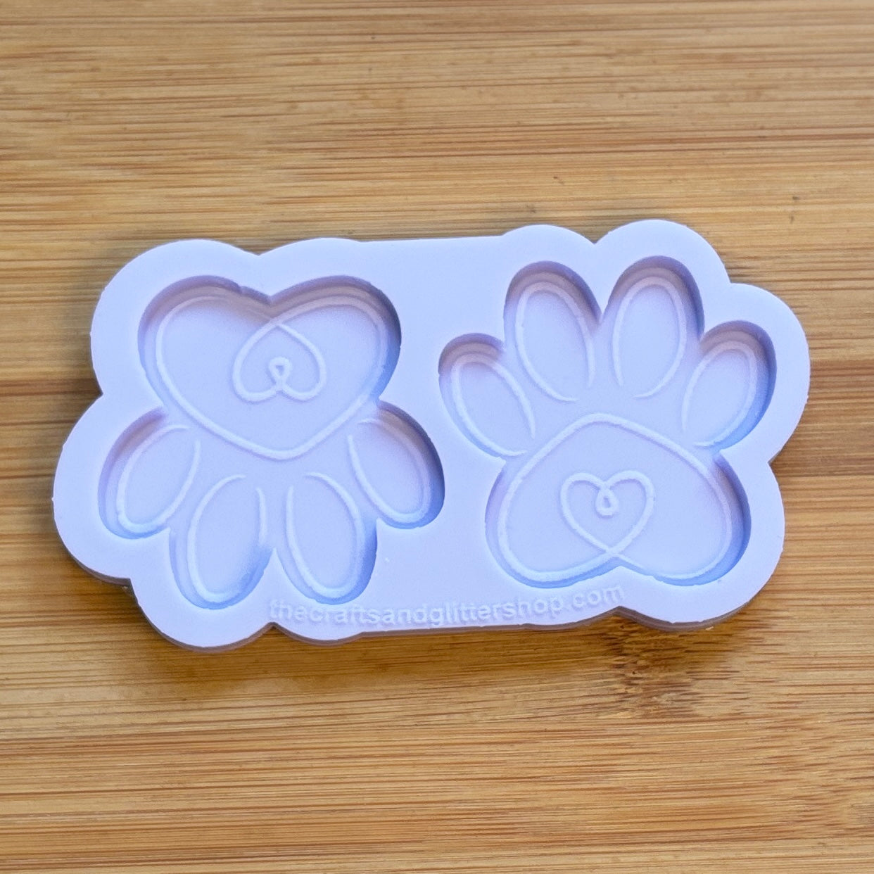 Silicone mold with heart and paw print designs on a wooden surface