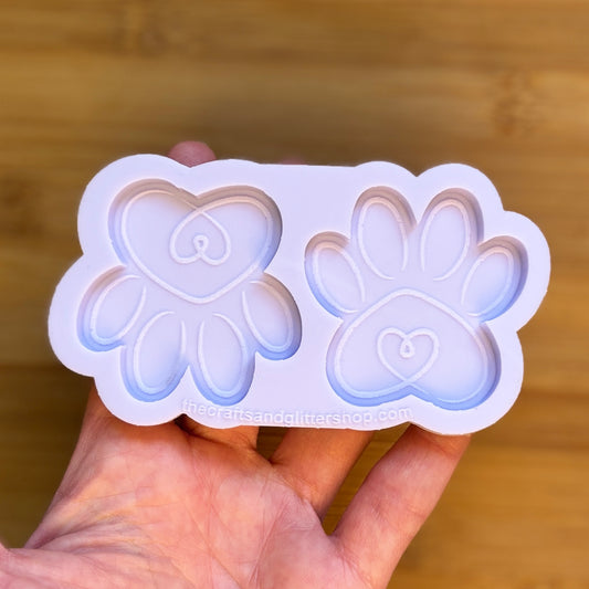 Hand holding a silicone mold with paw and heart designs against a wooden background