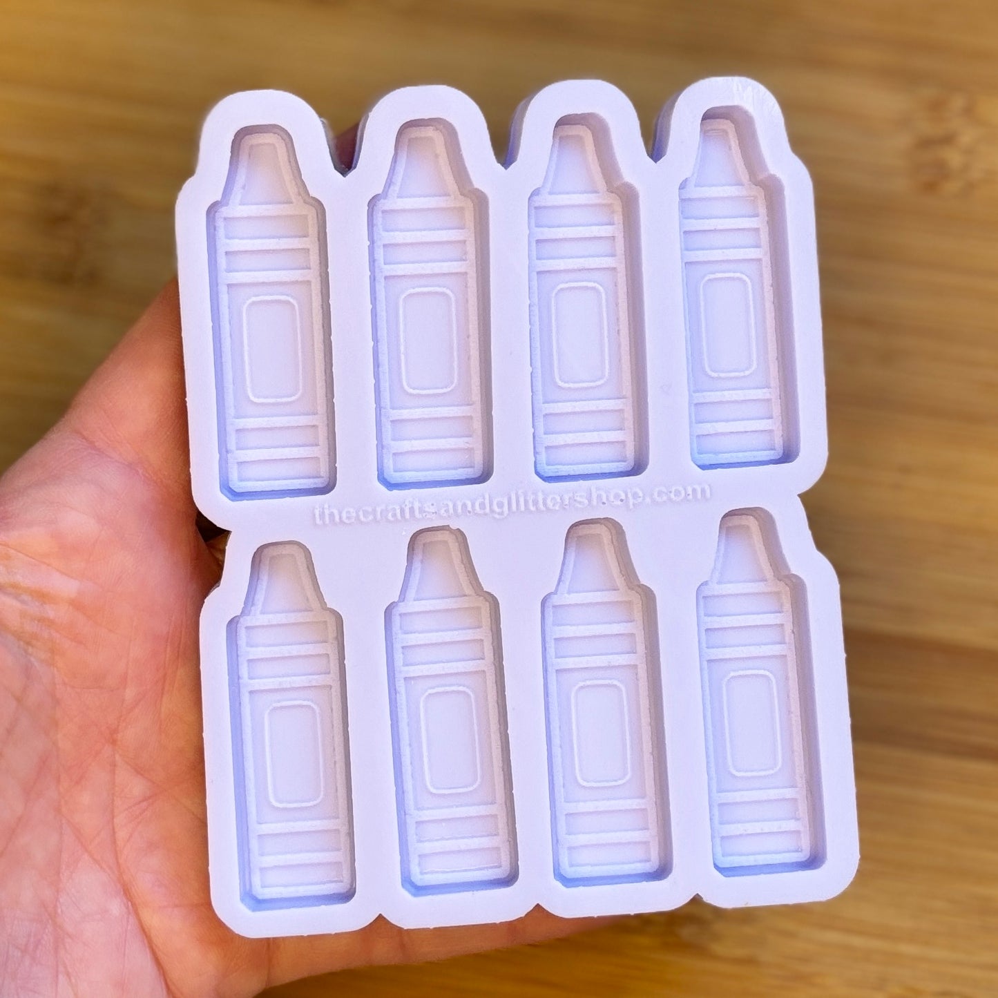 Silicone mold shaped like crayons held in a hand on a wooden surface