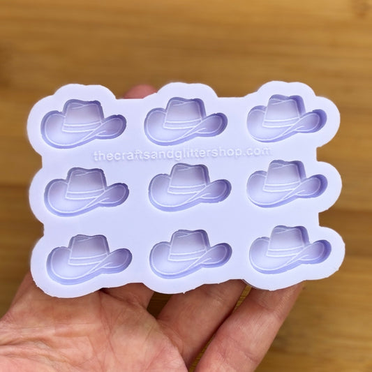 Silicone mold with cowboy hat shapes held by a hand on a wooden surface